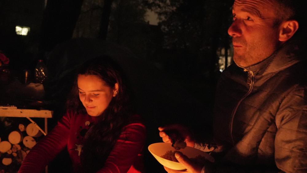 Isra et son père Miri partagent le repas du soir autour du feu. © Matis BILLER-GOEFFERS